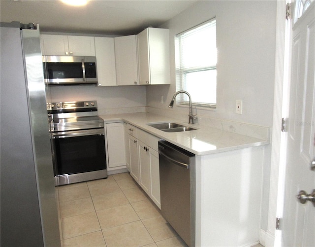 kitchen with white cabinetry, stainless steel appliances, sink, and light tile patterned floors