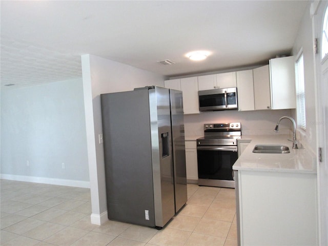 kitchen featuring white cabinetry, stainless steel appliances, sink, and light tile patterned floors