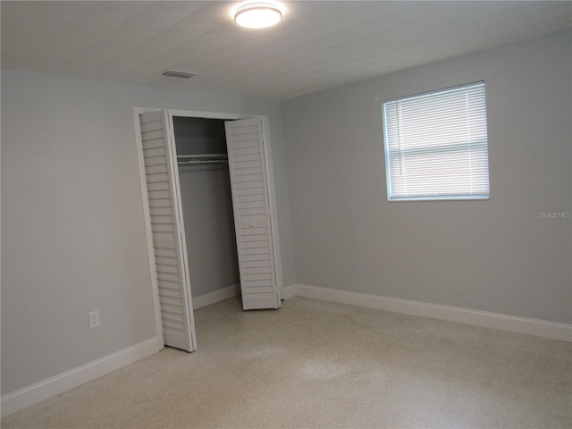 unfurnished bedroom featuring light carpet and a closet