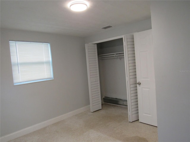 unfurnished bedroom with light colored carpet and a closet