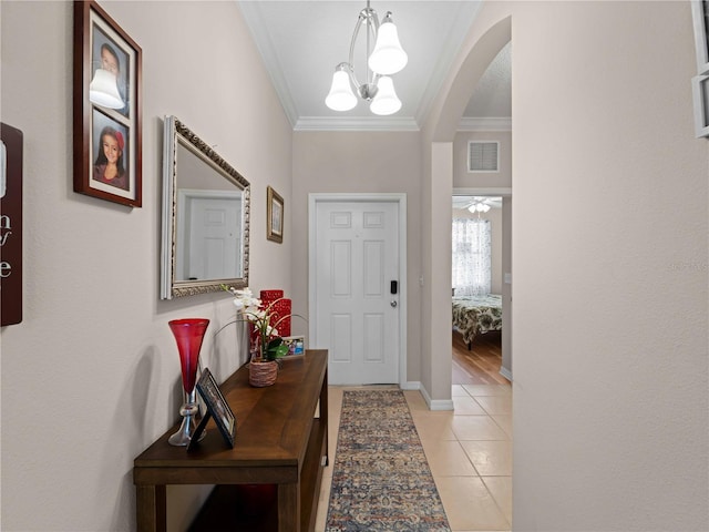 foyer entrance featuring an inviting chandelier, ornamental molding, and light tile patterned flooring