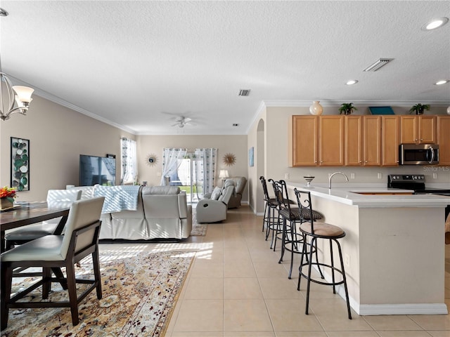 kitchen featuring light tile patterned floors, crown molding, a textured ceiling, and a kitchen bar