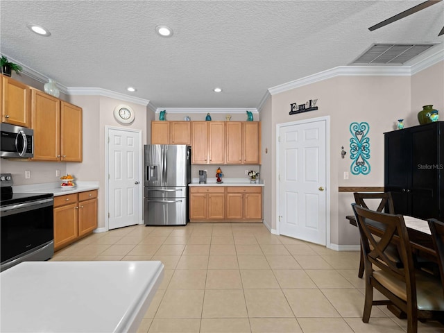 kitchen with light tile patterned floors, ornamental molding, a textured ceiling, and appliances with stainless steel finishes