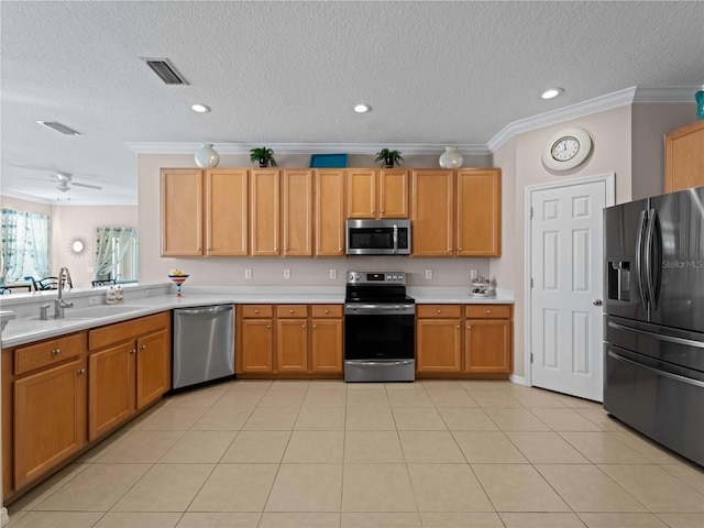 kitchen featuring sink, crown molding, a textured ceiling, light tile patterned floors, and appliances with stainless steel finishes