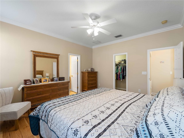 bedroom with ornamental molding, a spacious closet, hardwood / wood-style floors, and a closet