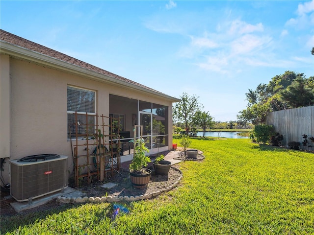 view of yard with cooling unit, a sunroom, and a water view