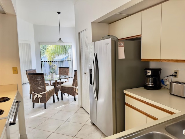 kitchen with stainless steel fridge, hanging light fixtures, and light tile patterned floors