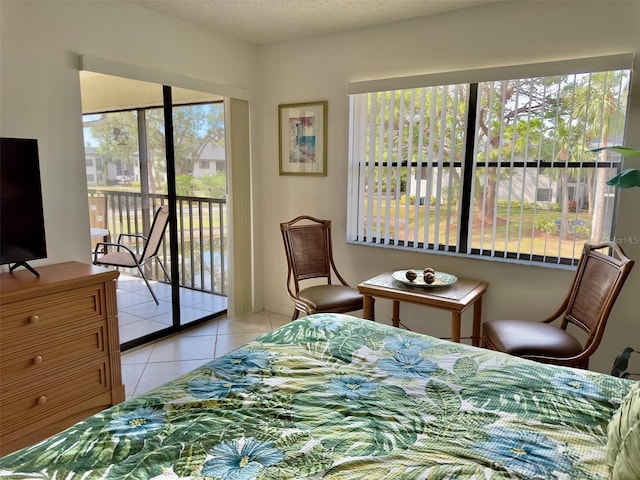 bedroom with multiple windows, access to outside, a textured ceiling, and light tile patterned floors