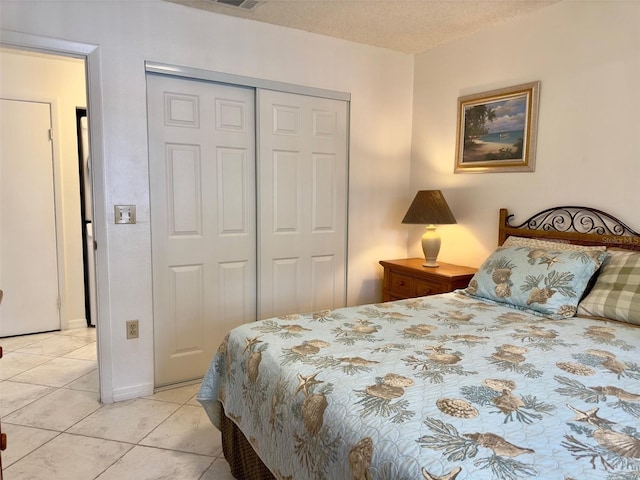 tiled bedroom with a closet and a textured ceiling