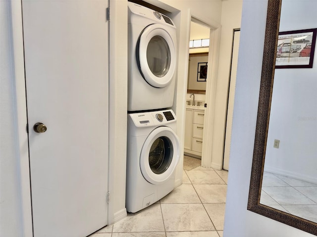 laundry area featuring stacked washing maching and dryer, sink, and light tile patterned floors