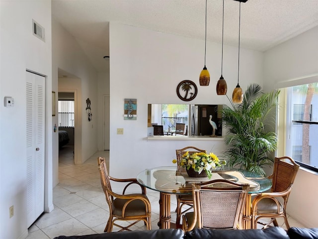 dining room featuring lofted ceiling, light tile patterned floors, and a textured ceiling