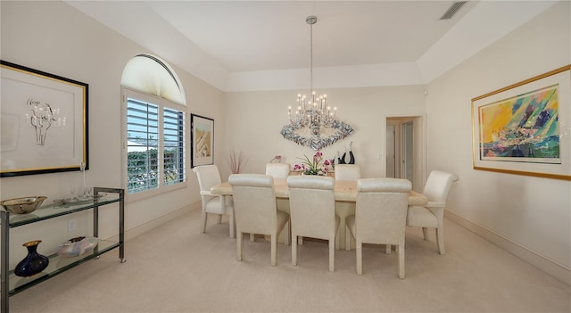 dining room with a raised ceiling, light carpet, and an inviting chandelier