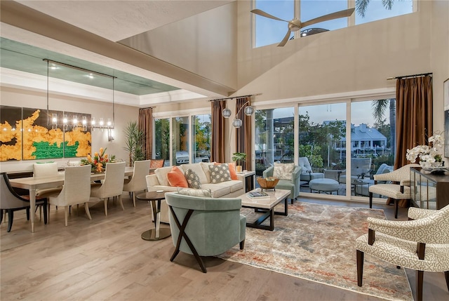 sunroom featuring a tray ceiling and ceiling fan with notable chandelier