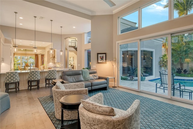 living room featuring crown molding, light hardwood / wood-style flooring, and a high ceiling