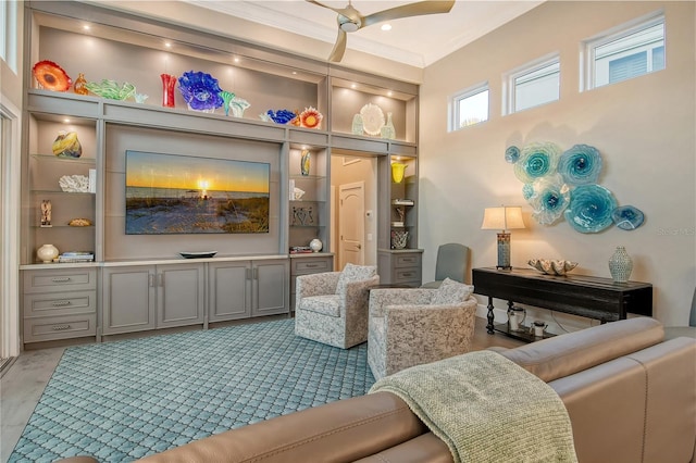 living room with a towering ceiling, built in features, ornamental molding, and ceiling fan