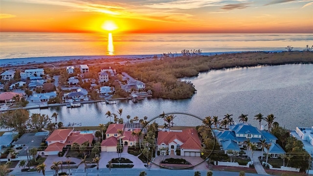 aerial view at dusk featuring a water view