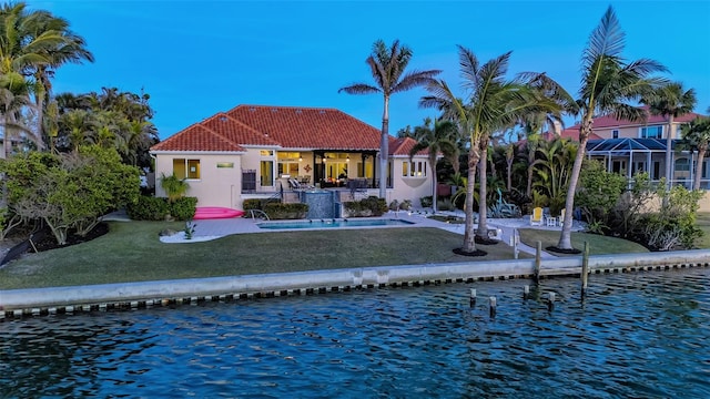 back of property featuring a patio, a water view, a yard, and pool water feature