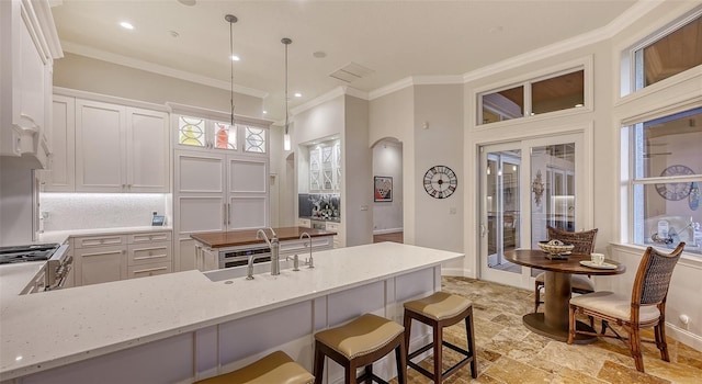 400 N Washington Dr, Sarasota, FL 34236 - kitchen with crown molding, light stone counters, white cabinets, light stone finish floors, and decorative light fixtures