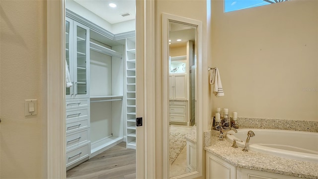 400 N Washington Dr, Sarasota, FL 34236 - bathroom featuring a bath, wood finished floors, and a spacious closet