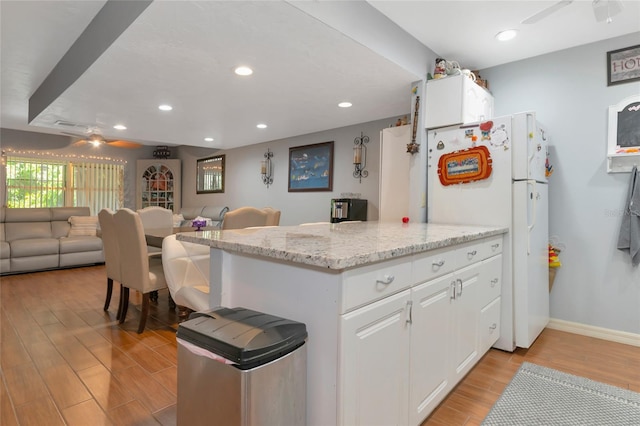 kitchen featuring white cabinetry, ceiling fan, light stone countertops, and white fridge