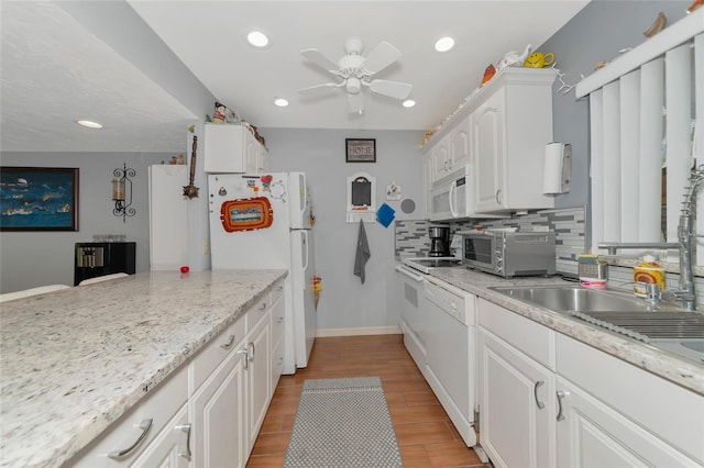 kitchen with white appliances, white cabinetry, backsplash, light stone countertops, and light wood-type flooring