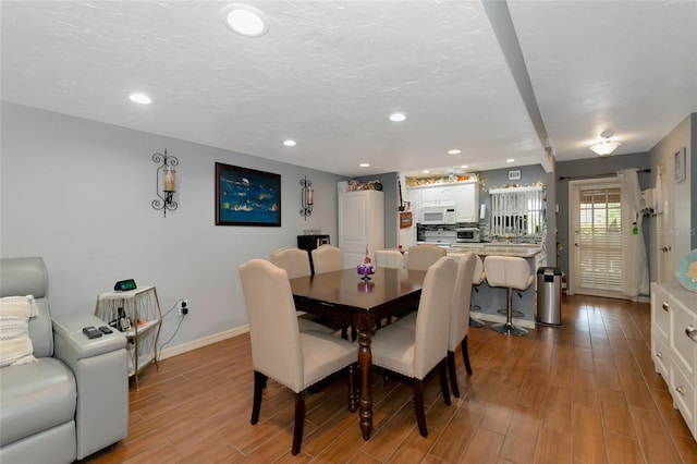 dining room featuring light hardwood / wood-style flooring and a textured ceiling