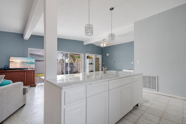 kitchen featuring pendant lighting, beam ceiling, light stone counters, and white cabinets