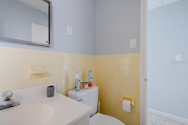 bathroom featuring vanity, tile walls, and toilet