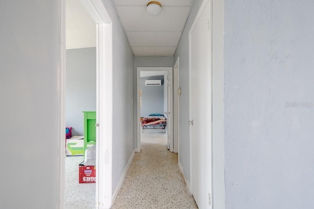 corridor with a paneled ceiling and a wall mounted air conditioner