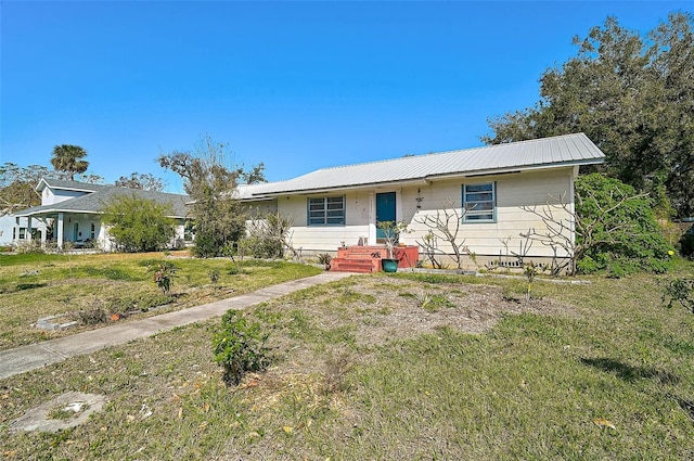 ranch-style home featuring metal roof and a front lawn