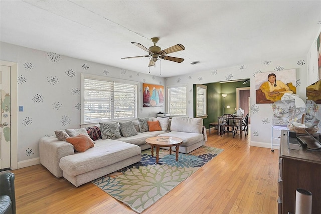 living area with baseboards, a ceiling fan, and light wood-style floors