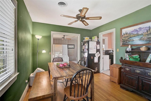 dining area with light wood-type flooring, ceiling fan, visible vents, and washer / clothes dryer