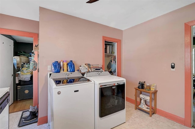 clothes washing area featuring light tile patterned floors, washer and clothes dryer, and baseboards