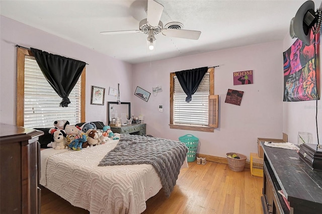 bedroom featuring light wood-type flooring, baseboards, and a ceiling fan