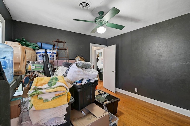 interior space with a ceiling fan, visible vents, baseboards, and wood finished floors