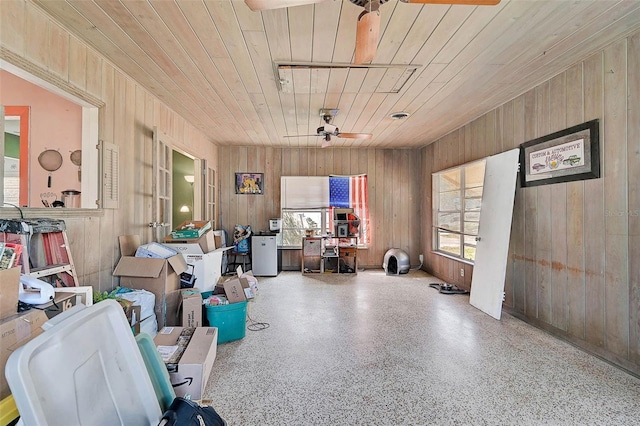 misc room with ceiling fan, speckled floor, wood ceiling, and wooden walls