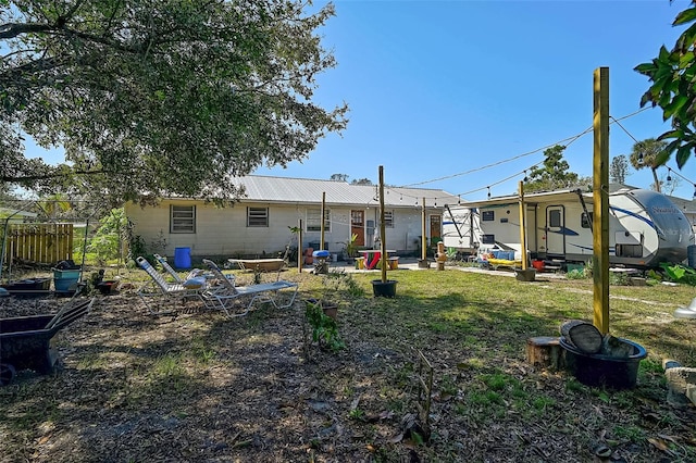 back of house featuring entry steps, fence, metal roof, and a yard