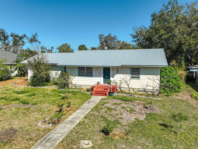 ranch-style home featuring metal roof and a front lawn