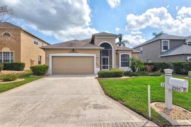 view of front of property featuring driveway, a front lawn, an attached garage, and stucco siding