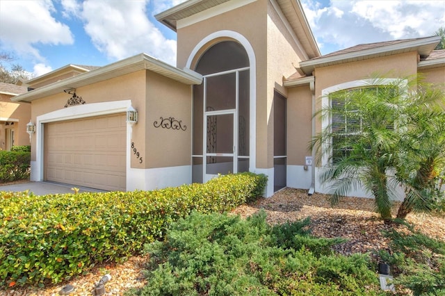 doorway to property featuring an attached garage and stucco siding