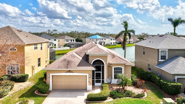 view of front of home featuring a garage, a water view, concrete driveway, a residential view, and stucco siding