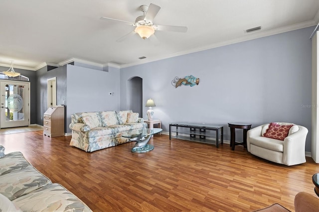 living area featuring baseboards, visible vents, arched walkways, ornamental molding, and wood finished floors