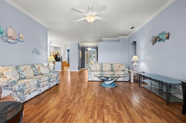 living room featuring a ceiling fan, crown molding, and wood finished floors