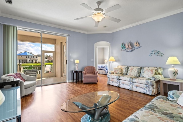 living room with arched walkways, crown molding, ceiling fan, wood finished floors, and baseboards