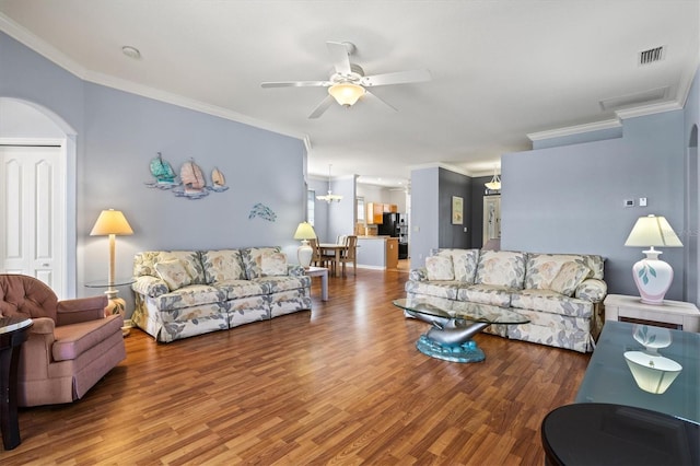 living area with ornamental molding, a ceiling fan, visible vents, and wood finished floors