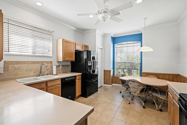 kitchen featuring a wainscoted wall, crown molding, light countertops, a sink, and black appliances