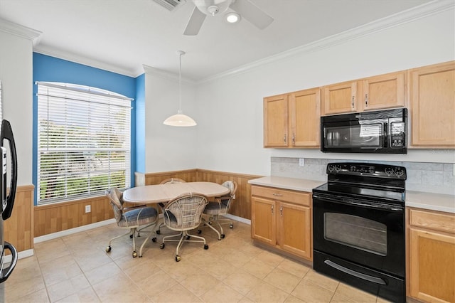 kitchen with black appliances, pendant lighting, light countertops, and a wainscoted wall