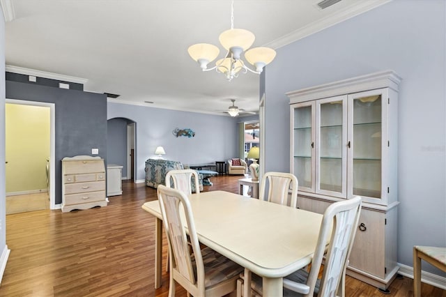 dining room featuring arched walkways, baseboards, dark wood-style floors, and crown molding