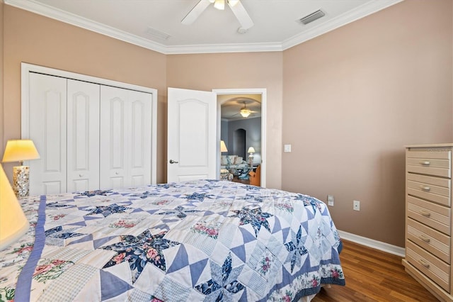 bedroom featuring wood finished floors, visible vents, baseboards, ornamental molding, and a closet