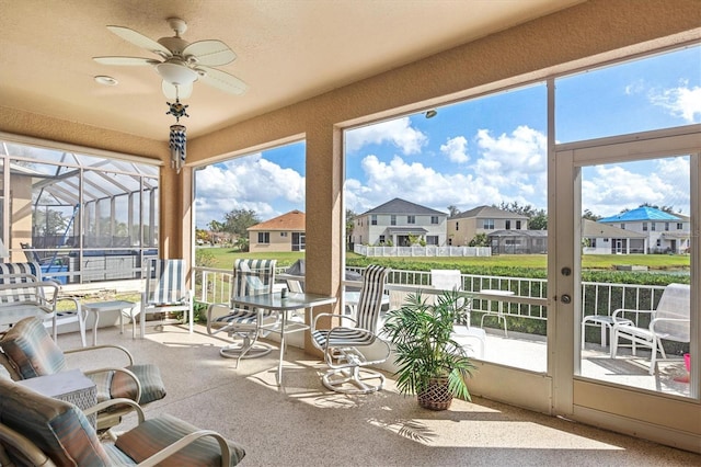 sunroom featuring ceiling fan and a residential view